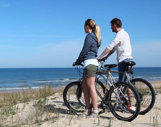 Man and woman with bikes on beach overlooking ocean