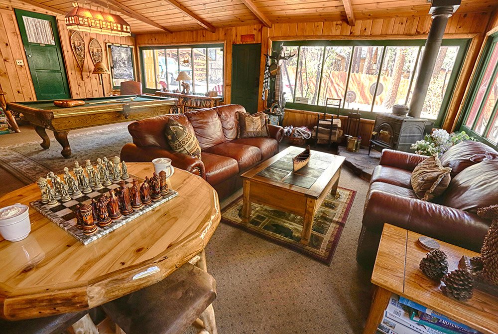 Living room with leather couches, pool table, chess board, and windows