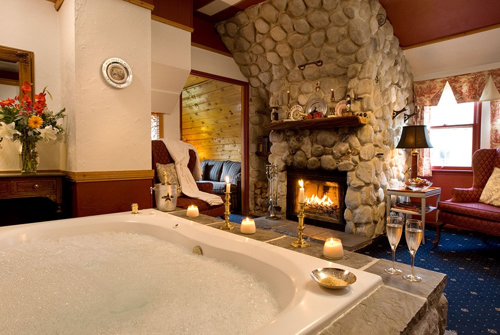 Large bathtub in bathroom with stone fireplace and comfy seating