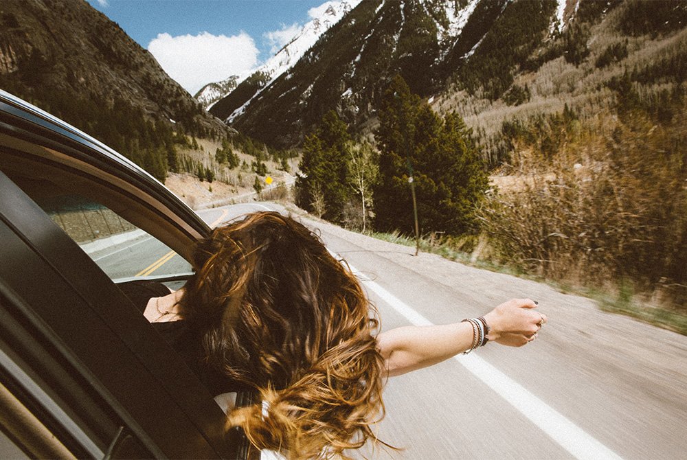 woman sticking head out the car window