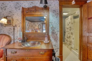 nightstand and vanity with a view into the bathroom