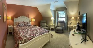 Queen-sized bed next to lamps and reclining chair