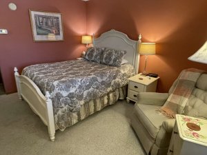Queen-sized bed next to lamps and reclining chair