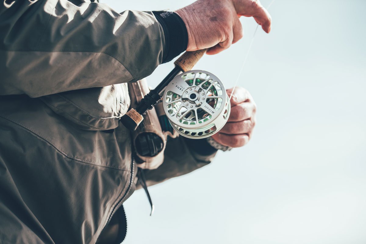 old angler's hands holding a fly rod