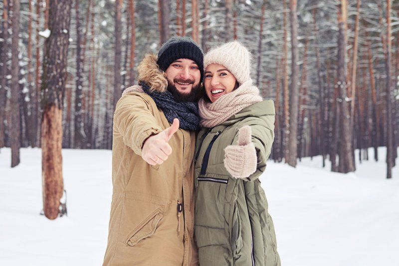 Couple with their thumbs up outside