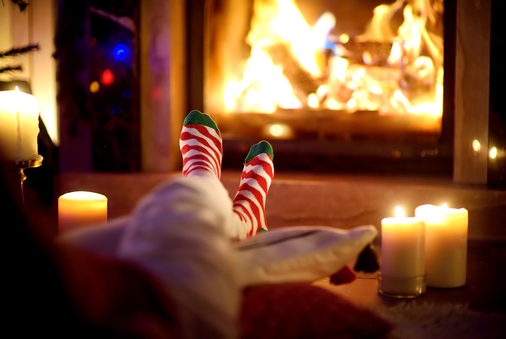 Person with their feet up sitting by the fire with candles